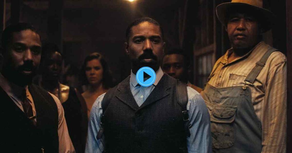 Michael B. Jordan looks directly at the camera while wearing a dark vest and backpack, framed by a man in a hat and overalls on the right and another man in a suit and tie on the left, with other figures obscured in the shadows behind him.