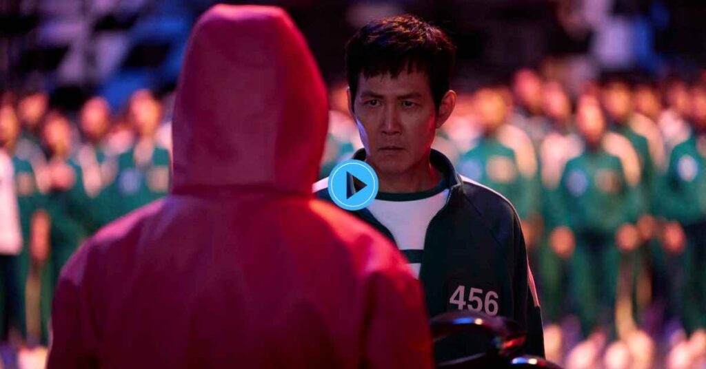 Lee Jung-jae as Seong Gi-hun (Player 456) wearing his green tracksuit, standing face-to-face with a red-hooded guard in a dramatic scene from the Netflix series Squid Game.