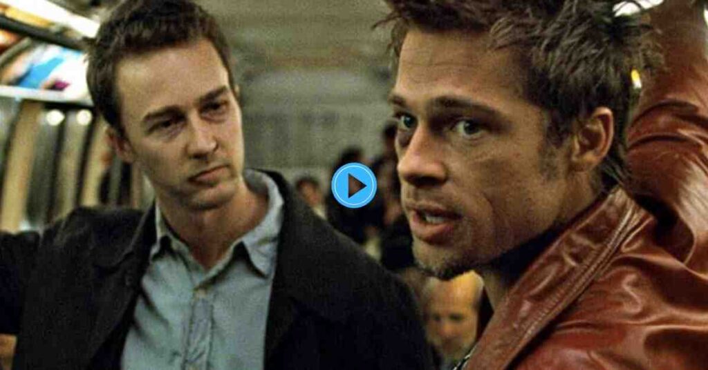 The Narrator (Edward Norton) looking concerned next to Tyler Durden (Brad Pitt) who is speaking, both on a public transit train in a still from the film Fight Club.