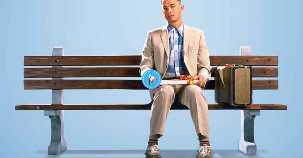 The iconic movie poster for Forrest Gump featuring Tom Hanks sitting alone on a park bench, holding a box of chocolates with a suitcase next to him, against a plain blue background.